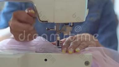 缝纫室里漂亮的女裁缝金发在缝纫机上缝制织物。 手和缝纫针的特写镜头